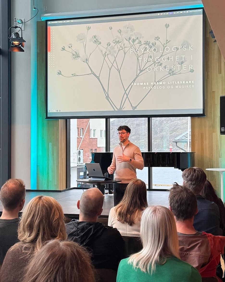 Thomas Husmo Litleskare holder foredrag foran et lerret med tittelen Psykologisk trygghet i orkester